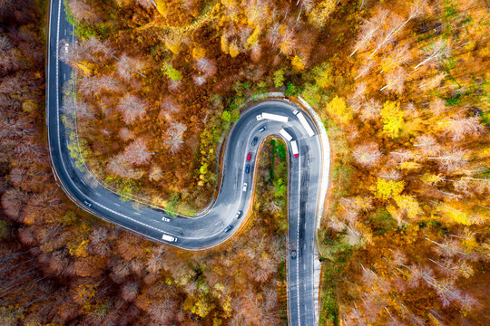 Winding curved road with cars and trucks on the road. Aerial view.