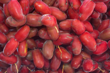 Closeup, Ripe red fruits dates swaying to the wind on date palm. Background red fruits dates