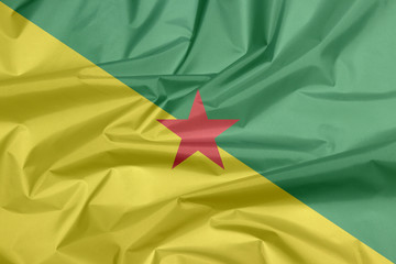 Fabric flag of French Guiana. Crease of French Guiana flag background, The green and yellow with red star.
