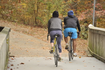 A couple biking through the woods with autumn foliage