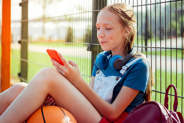 Waiting for date. Joyful girl keeping smile on her face while choosing favorite song