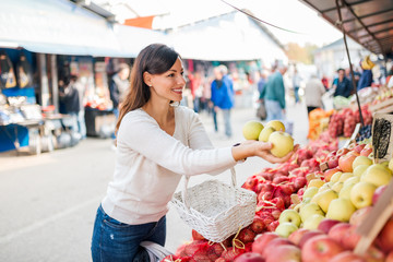 Beautiful young woman shopping at local food market.