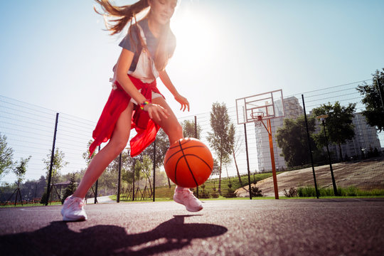 Sport uniform. Concentrated girl looking at ball while playing basketball