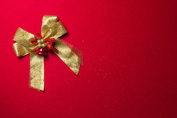 Golden ribbon bow with decorations on red flannel background, top view design