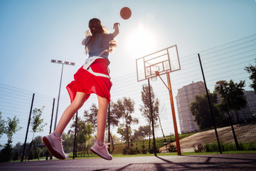 Love sport. Cheerful teenager throwing ball up while jumping high