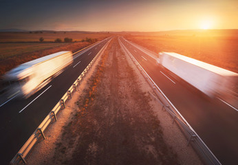 Trucks in the highway, dramatic sunset, motion blur. Cargo, transportation concept
