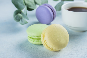 Delicious colorful pastel macarons with cream and coffee cup. Coffee break scene with macaron candy