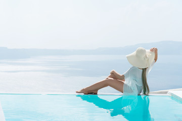 young woman enjoying a magnificent view of Santorini near the pool.