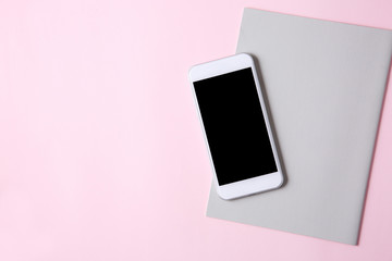 ピンク背景に白いスマートフォンとノート