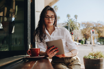 Woman sitting at a cafe working on digital tablet