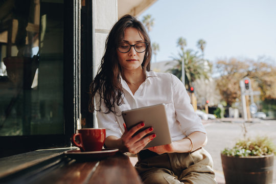 Woman Sitting At A Cafe Working On Digital Tablet