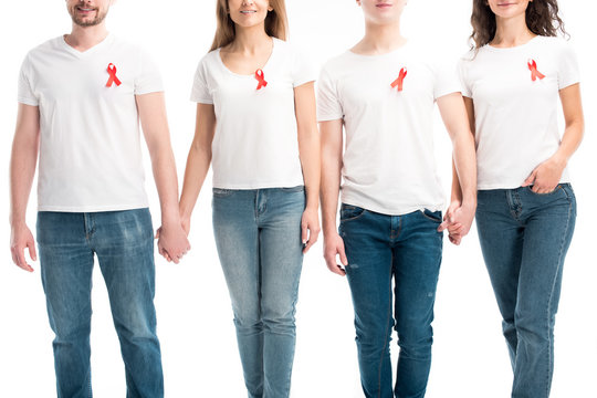 cropped image of men on women with red ribbons holding hands isolated on white, world aids day concept