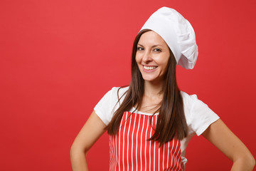 Housewife female chef cook or baker in red striped apron, white t-shirt, toque chefs hat isolated on red wall background. Close up portrait of housekeeper brunette woman. Mock up copy space concept.