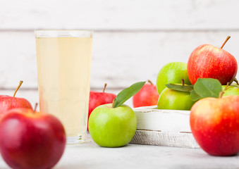 Glass of fresh organic apple juice with red and green apples in box on wooden background