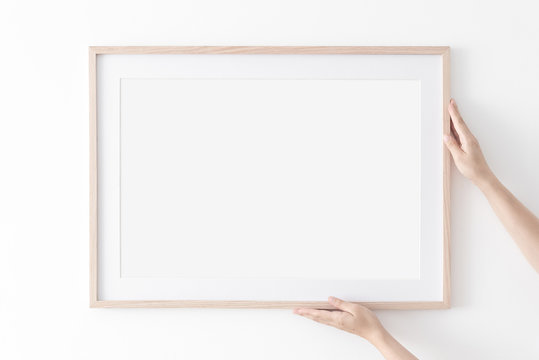 Landscape large 50x70, 20x28, a3,a4, Wooden frame mockup with passe-partout on white wall in women hands. Poster mockup. Clean, modern, minimal frame. Empty fra.me Indoor interior, show text or