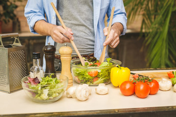 Man cooking healthy simple vegetarian food at home in the kitchen sunny evening. Healthy food concept. Close-up.