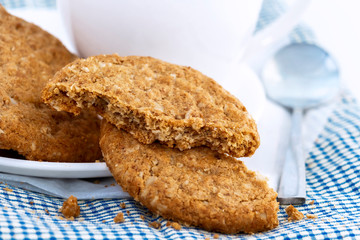 Homemade shortbread cookies made of oatmeal are stacked with hot coffee cup on cloth and paper on white table background. Concept food healthy snack for enjoy in holiday.