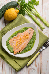 trout over cucumber cream decorated with lemon peel