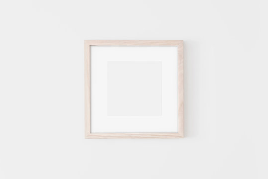 Square Wooden frame mockup with passe-partout on white wall. Poster mockup. Clean, modern, minimal frame. Empty fra.me Indoor interior, show text or product