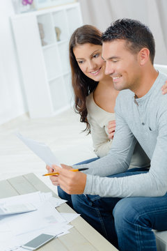 smiling couple with documents in home