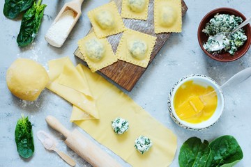 Cooking Raviolli homemade pasta with ricotta and spinach on a blue background, traditional Italian...