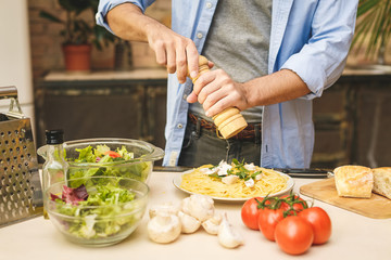 Close-up of young man preparing delicious and healthy food in the home kitchen on a sunny day.