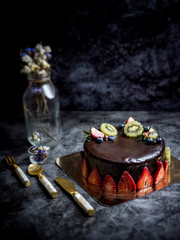 sweet pastry dessert chocolate cake with strawberry, kiwi and blueberry set on kitchen table.