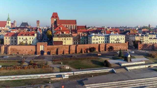 Torun old city in Poland. Aerial flyby video in sunrise light with medieval Gothic St John Cathedral, town hall tower, Vistula river, historic buildings, town walls and gates