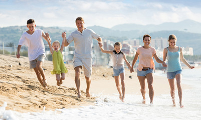 Carefree family of six people happily running on beach