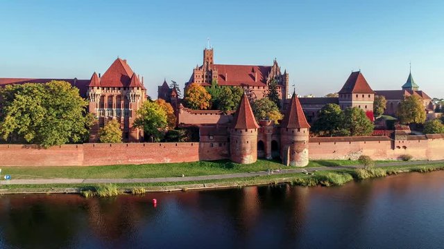 Medieval Malbork (Marienburg) Castle in Poland, main fortress of the Teutonic Knights at the Nogat river. Aerial flyby 4K video in sunset light