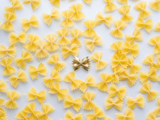 Pattern of yellow pasta with golden one in the centre at white background.