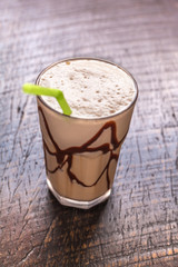 White Frappe Coffee Glass with iced drink on a dark wooden table in a cafe. color correction filter
