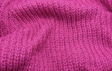 Fototapeta na wymiar Texture of a pink knitted sweater closeup, red knitted wool
