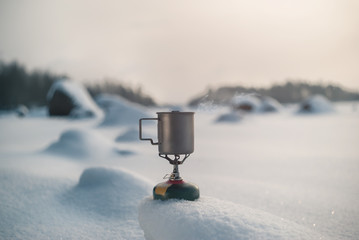 Boiling tea in a titanium mug on a gas burner. Outdors. Winter time