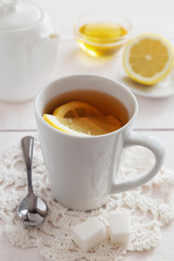 Cup of lemon tea with honey and a teapot