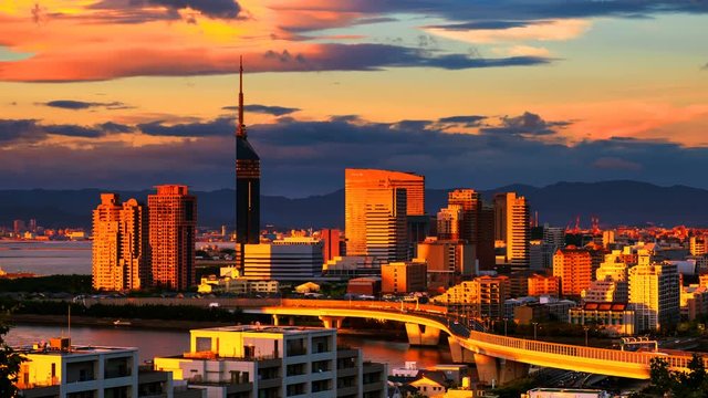 Fukuoka, Japan. A sunset video with a view of central Fukuoka, Japan, with tall modern buildings standing by the Hakata Bay on a cloudy summer day. Time-lapse from day to night