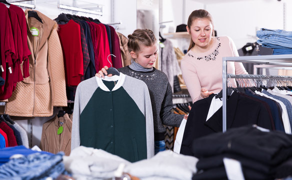 Glad teen girl looking for clothing with mum