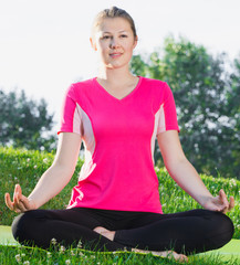 Adult female in pink T-shirt is sitting and meditating