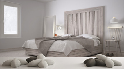 Fototapeta na wymiar White table, desk or shelf with five soft white pillows in the shape of stars or flowers, over blurred bedroom, bed with wooden headboard, minimal architecture interior design concept