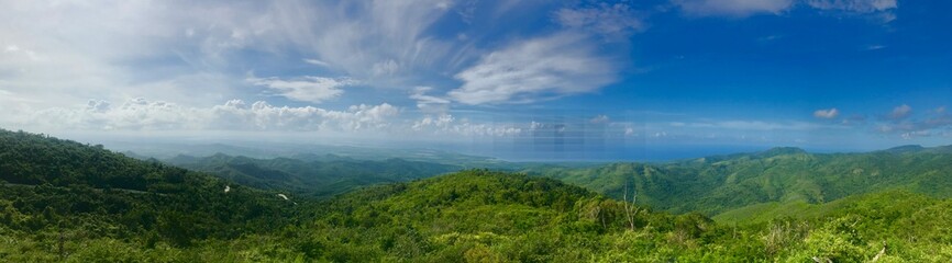 Fototapeta na wymiar Mirador Lookout Point Panorama close to Trinidad (Sancti Spiritus) in the Cuban Countryside (Caribbean island) with a lush green vegetation and a blue summer sky with white clouds