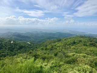 Fototapeta premium Mirador Lookout Point Panorama View close to Trinidad (Sancti Spiritus) in the Cuban Countryside (Caribbean island) with an untouched lush green vegetation and a blue summer sky with white clouds 