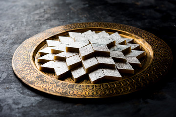Kaju Katli is a Diamond shape Indian sweet made using cashew sugar and mava, served in a plate or bowl over moody background. selective focus
