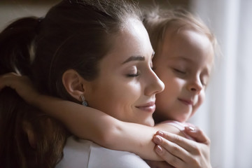 Close up portrait young beautiful sincere woman mother embrace hug little preschool girl daughter make peace after quarrel. Happy motherhood, custody guardianship new mother for adopted child concept