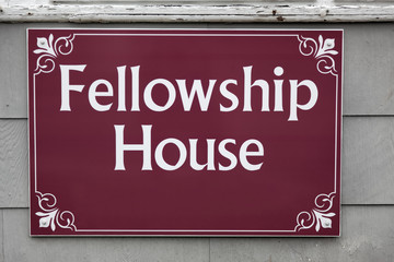 Fellowship House sign against outdoor wall.