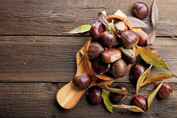 Fresh chestnuts in a bowl on an old wooden table.