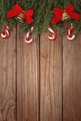 Christmas composition of tree branches, candies and decorations on wooden background. Top view. Copy space.
