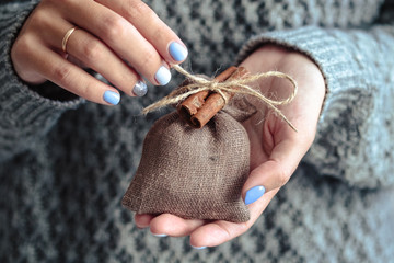 Gorgeous manicure, pastel tender color nail polish, closeup photo. Female hands hold a simple gifts over knit grey background