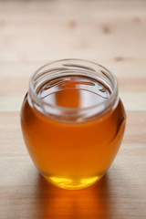 Young light floral honey is poured into a glass jar.
