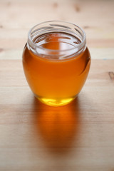 Young light floral honey is poured into a glass jar.