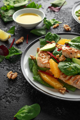 Grilled chicken with orange and avocado salad on rustic background